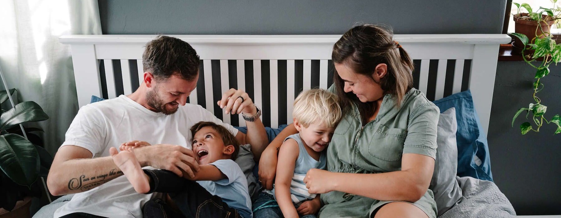 parents play with their children on a bed